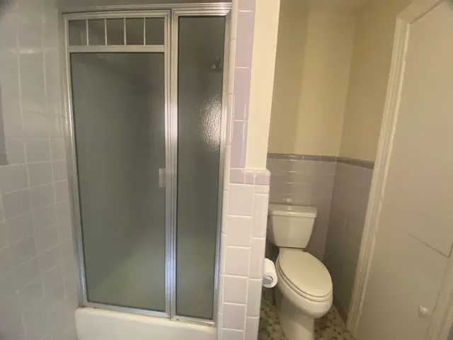 a white toilet sitting next to a shower