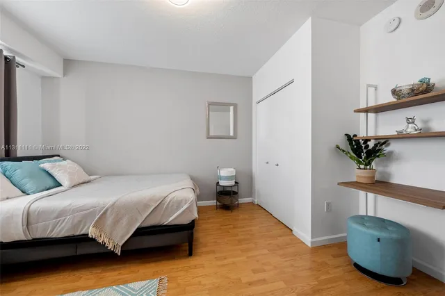 a bedroom with a bed and a potted plant on the dresser