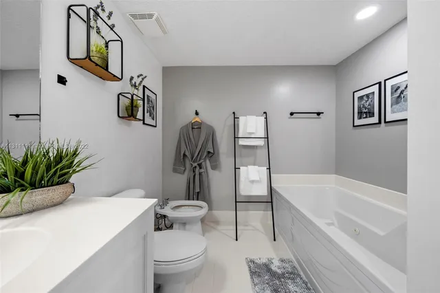 a bathroom with a granite countertop sink mirror vanity bathtub and toilet