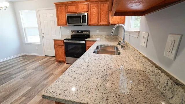 a kitchen with granite countertop a stove a sink and a microwave