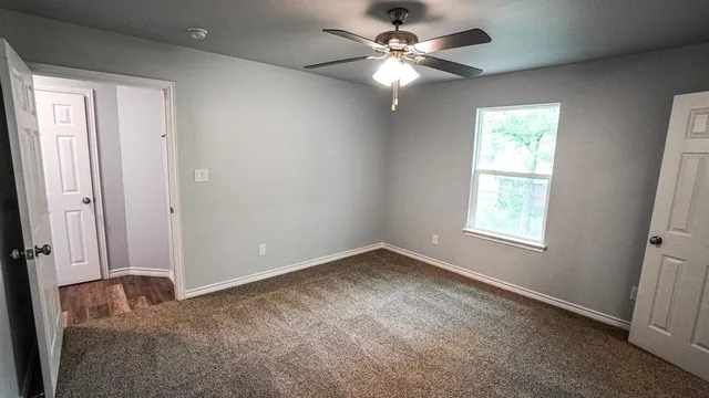 an empty room with windows and fan