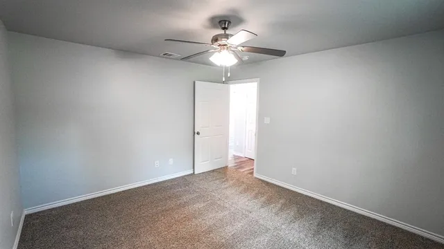 an empty room with a chandelier fan and windows