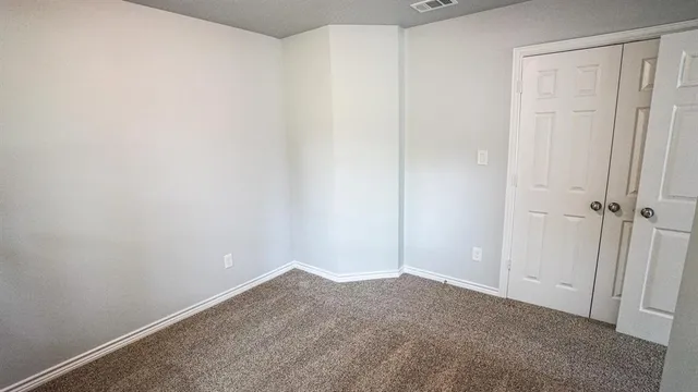 an empty room with an entryway and refrigerator
