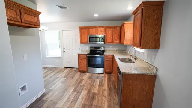 a kitchen with stainless steel appliances granite countertop a sink stove and refrigerator