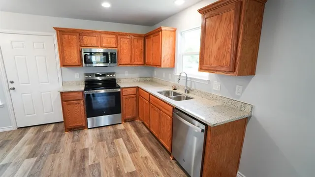 a kitchen with stainless steel appliances a sink dishwasher stove and wooden cabinets