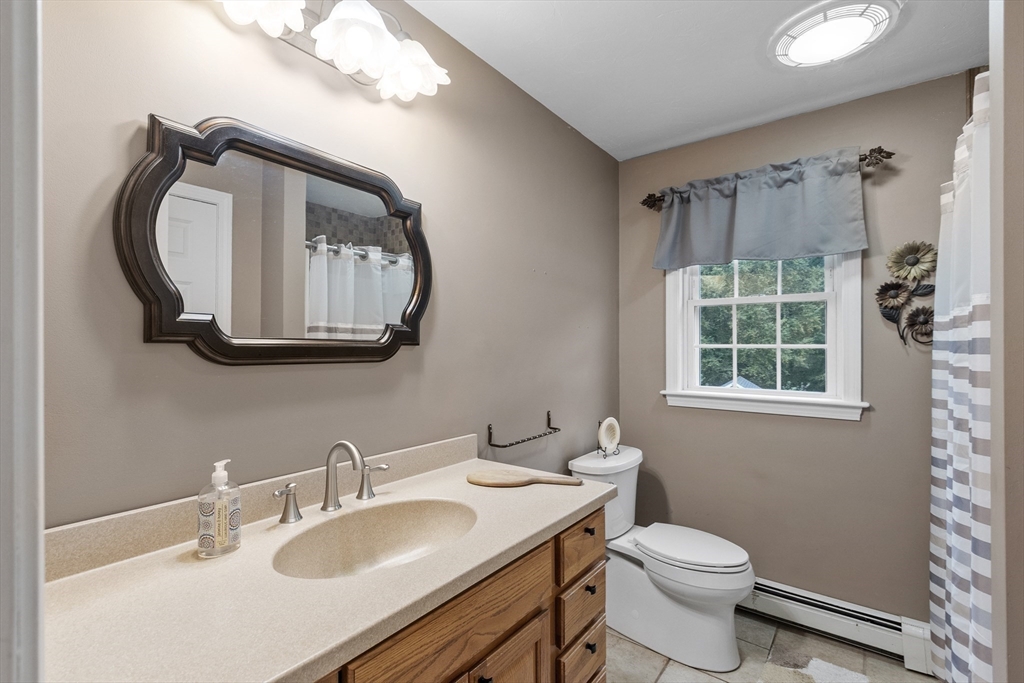 74 King Road Charlton, MA 01507 - Photo 18 of 38 a bathroom with a toilet a sink a mirror a window and vanity