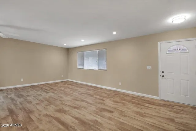 a view of an empty room with wooden floor and a window
