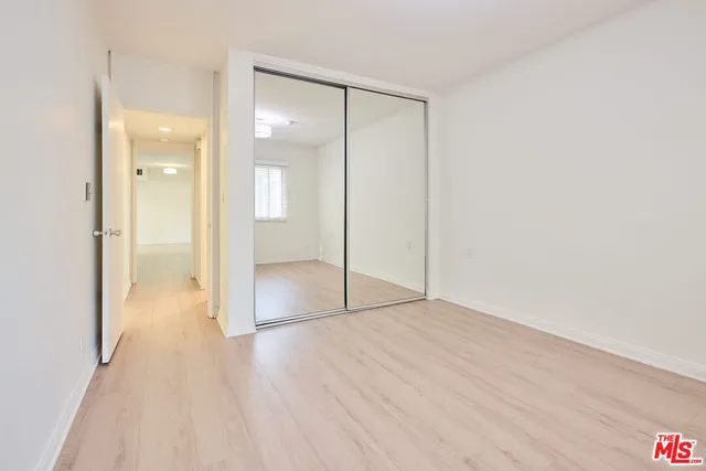 a view of an empty room with wooden floor and a bathroom