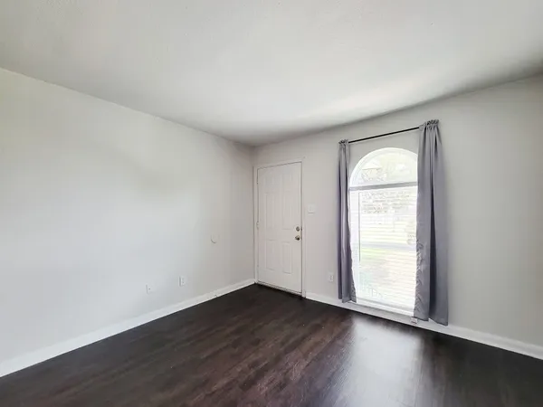 an empty room with wooden floor and window