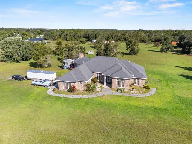 a view of a white house with a big yard and large trees