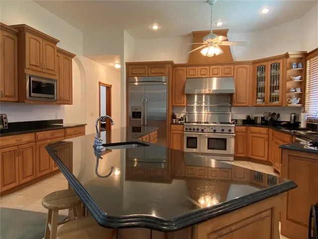a kitchen with stainless steel appliances granite countertop a sink a stove and a refrigerator