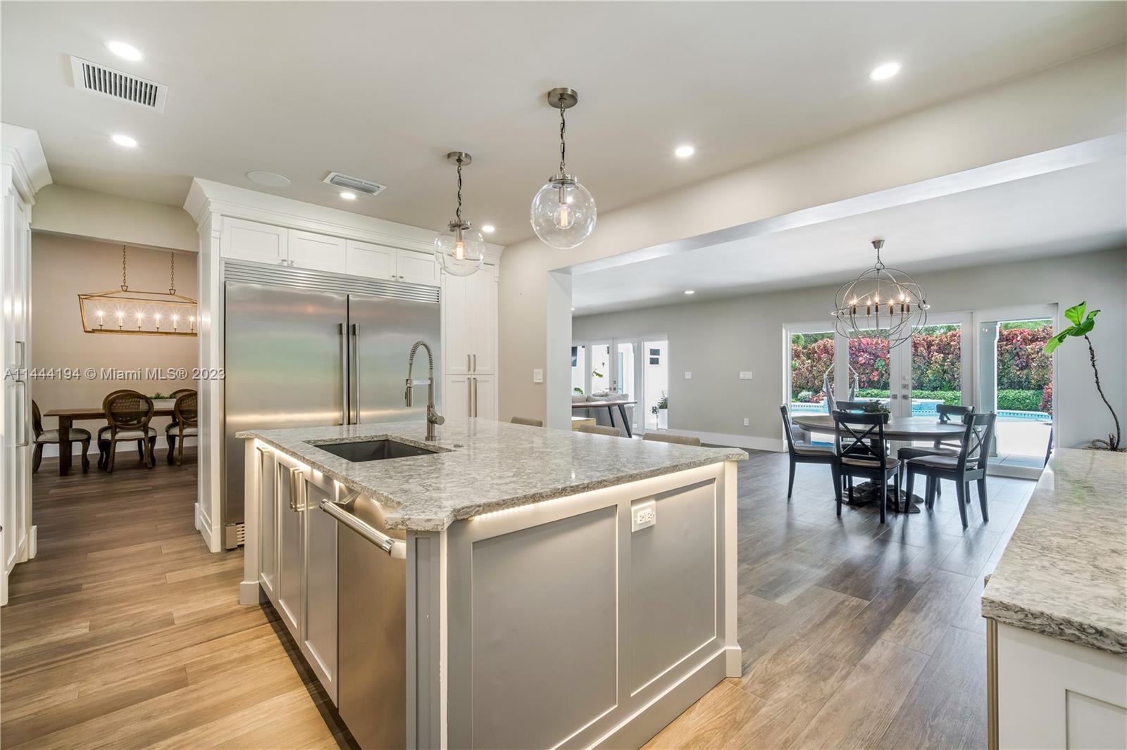 7900 Southwest 129th Terrace Pinecrest, FL 33156 - Photo 8 of 57 a kitchen with stainless steel appliances granite countertop a stove oven a dining table chairs and couches with wooden floor