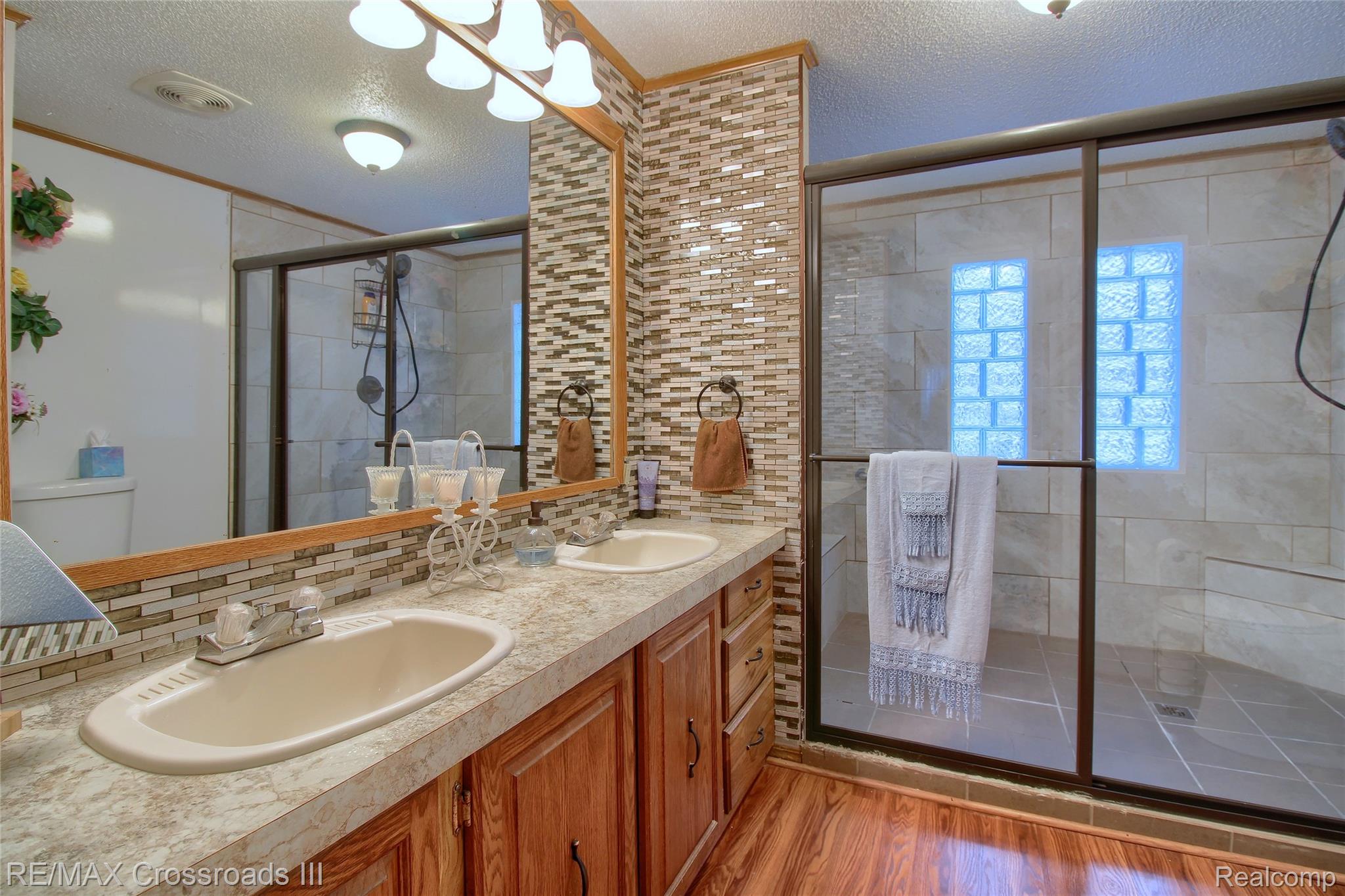 48620 Wear Road Belleville, MI 48111 - Photo 16 of 24 Full bath with a textured ceiling, double vanity, light wood-style flooring, a shower stall, and tasteful backsplash