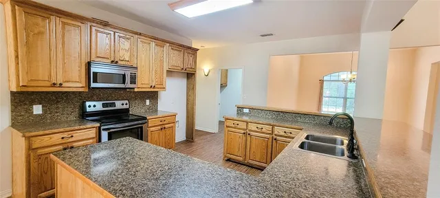 a kitchen with stainless steel appliances granite countertop a stove top oven a sink dishwasher and a refrigerator