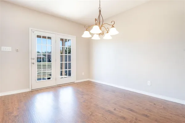 a view of a livingroom with a large window wooden floor and chandelier