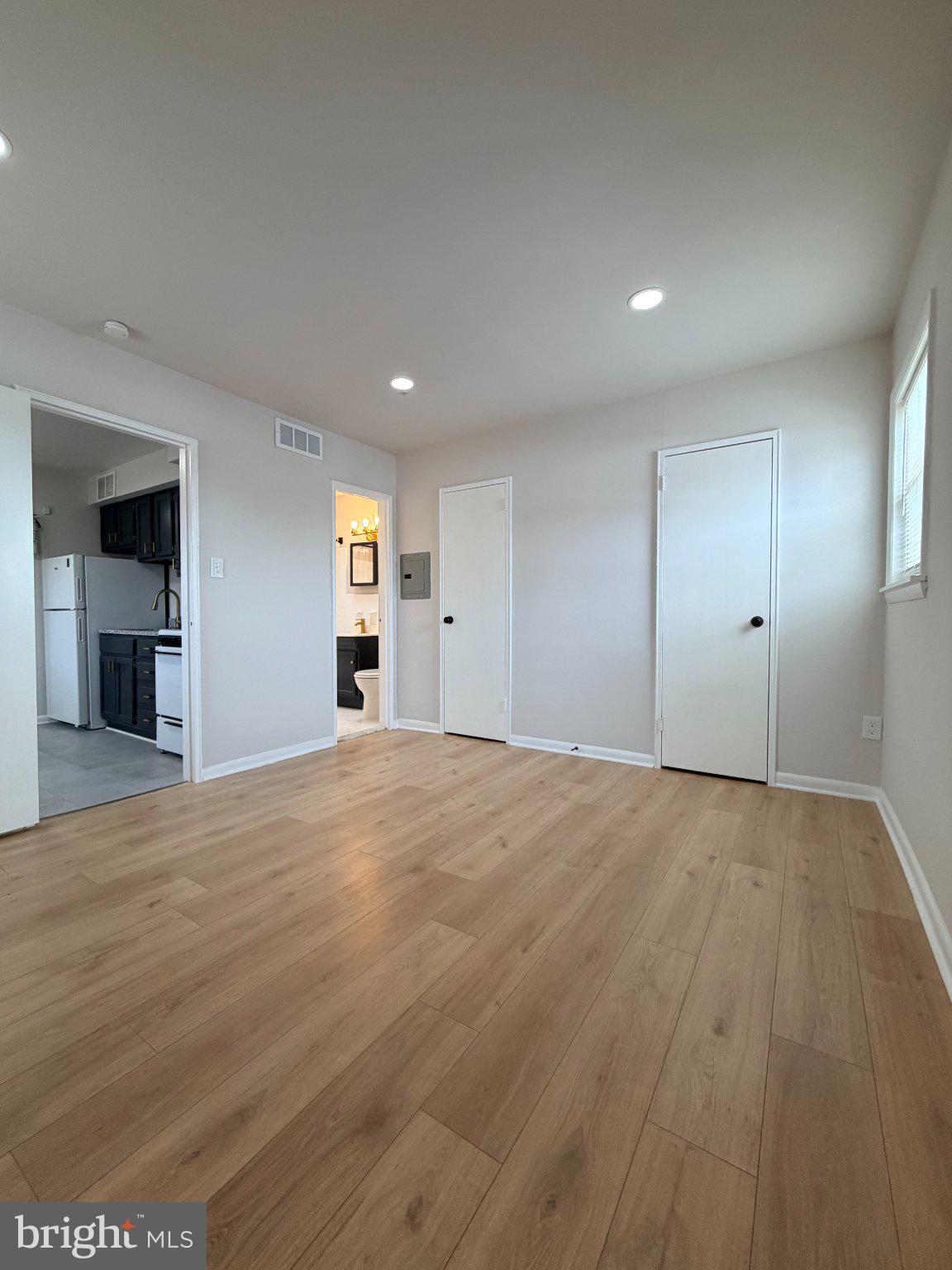 an empty room with wooden floor and windows