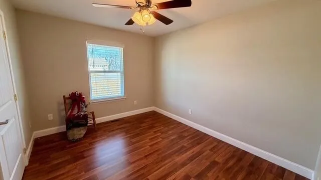 an empty room with wooden floor closet and chandelier fan