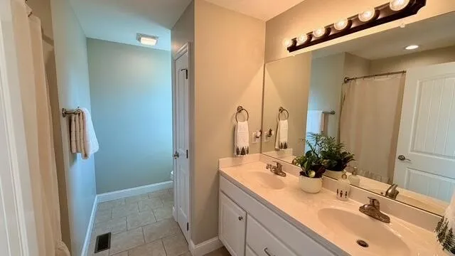 a en suite bathroom with a double vanity sink and a mirror