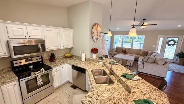 a open kitchen with stainless steel appliances granite countertop a stove a sink dishwasher a dining table and chairs with wooden floor