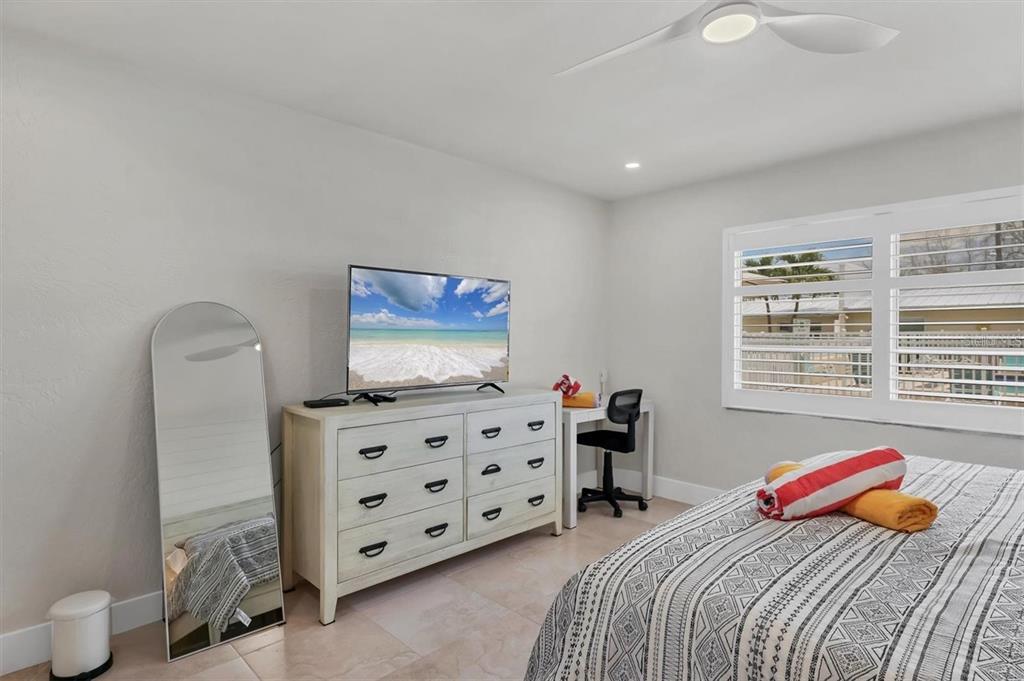 5830 Midnight Pass Road, Unit 54 Sarasota, FL 34242 - Photo 12 of 36 a bedroom with bed and a flat tv screen on dresser