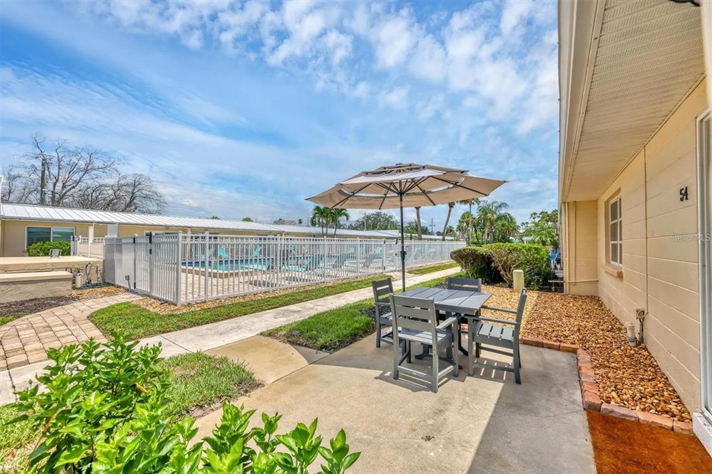 5830 Midnight Pass Road, Unit 54 Sarasota, FL 34242 - Photo 16 of 36 a view of a patio with chairs under an umbrella