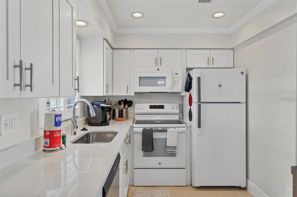 5830 Midnight Pass Road, Unit 54 Sarasota, FL 34242 - Photo 9 of 36 a kitchen with refrigerator a stove and white cabinets