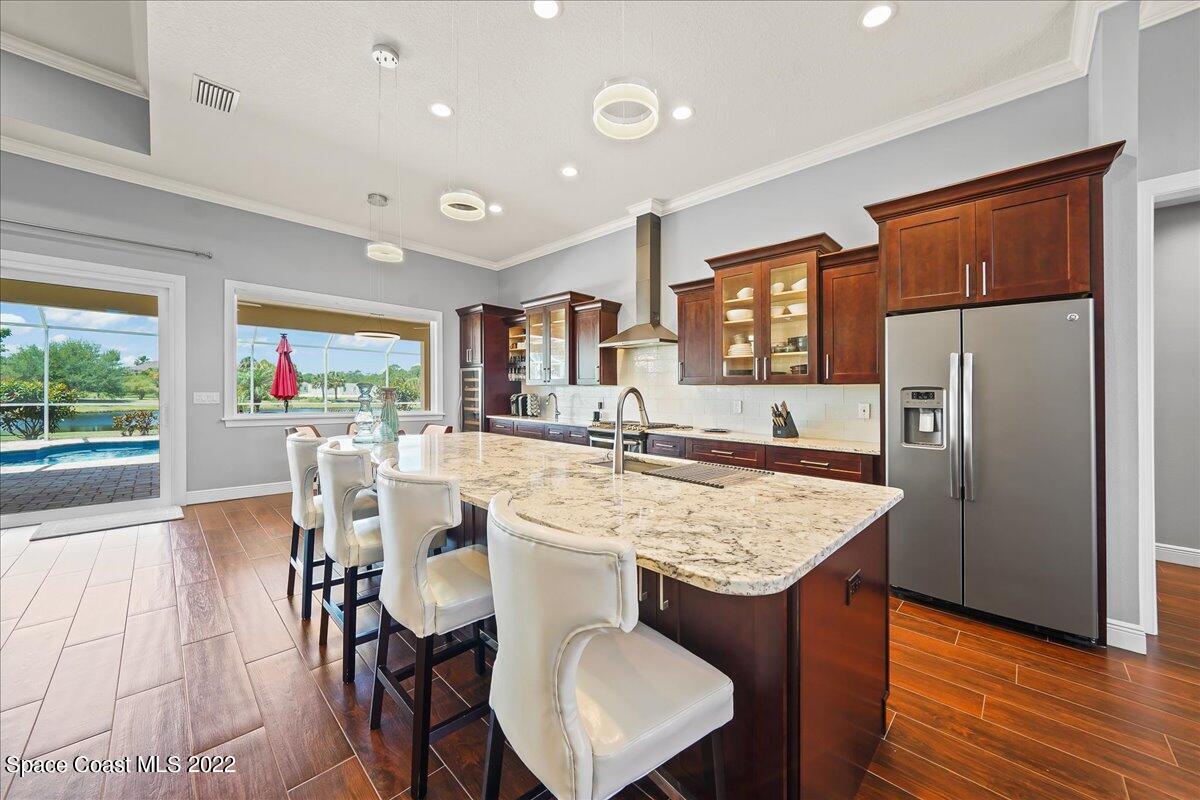 1360 Corey Road Malabar, FL 32950 - Photo 5 of 48 a kitchen with stainless steel appliances granite countertop a dining table chairs refrigerator and sink