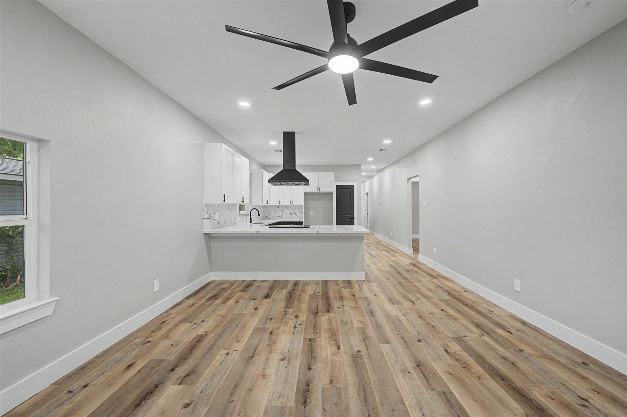 2338 Lidstone Street Houston, TX 77023 - Photo 11 of 17 Open-concept space features a sleek kitchen with white cabinetry and L-Shaped counters. The recessed lighting creates a bright and inviting atmosphere.