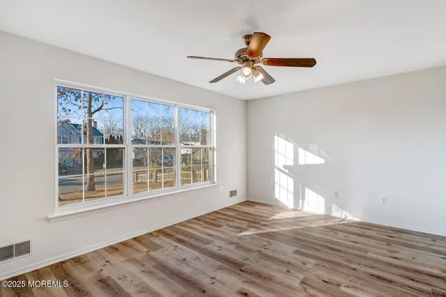 a view of an empty room with a window and wooden floor
