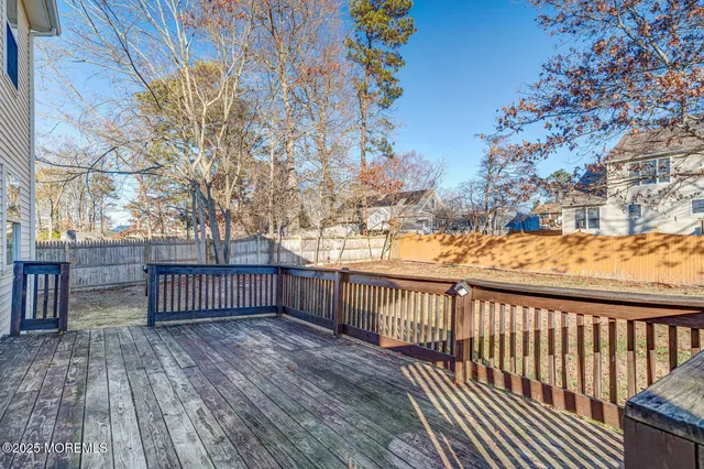 a view of deck with wooden floor and fence with a large tree