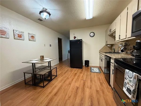 a kitchen with stainless steel appliances wooden floor and a refrigerator