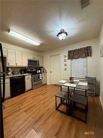 a kitchen with a table chairs a sink dishwasher stove and cabinets with wooden floor