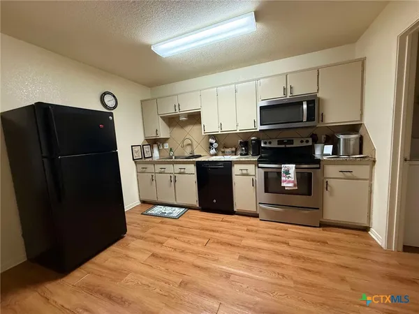 a kitchen with stainless steel appliances granite countertop a refrigerator stove a sink and dishwasher with wooden floor