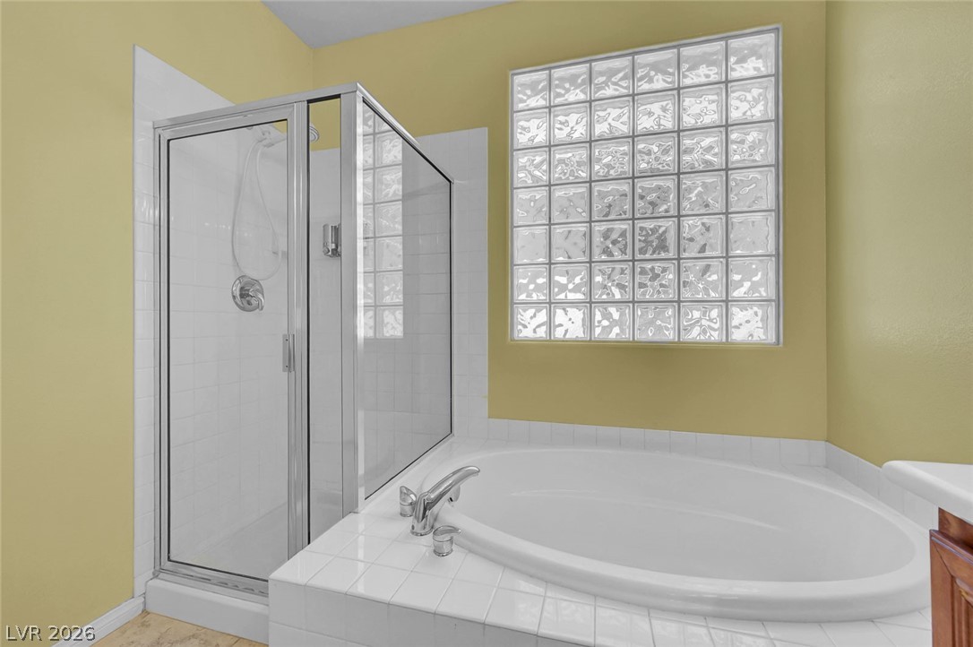 977 Sparkling Light Street Henderson, NV 89052 - Photo 47 of 75 Relax and refresh in this bright bathroom featuring a spacious tub and glass-enclosed shower.