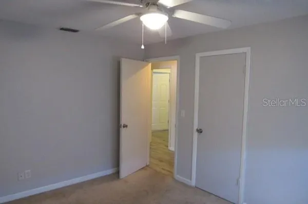 an empty room with a bathroom and a chandelier fan