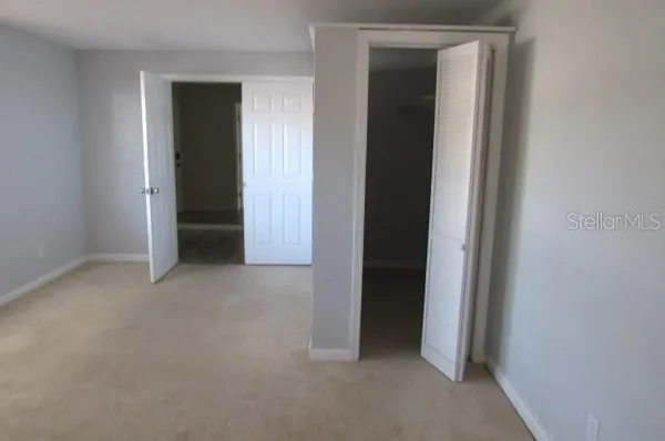 a view of an empty room with closet and bathroom