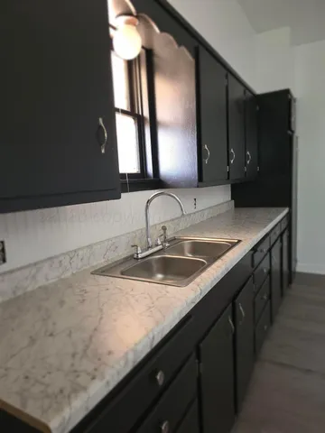 a view of an empty room with wooden floor and window