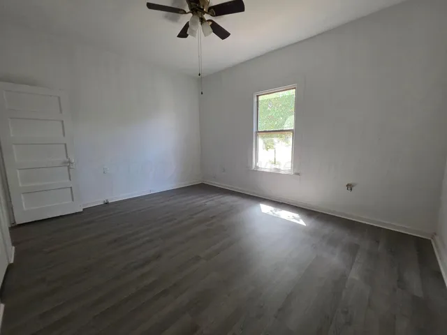 a view of an empty room with wooden floor and closet