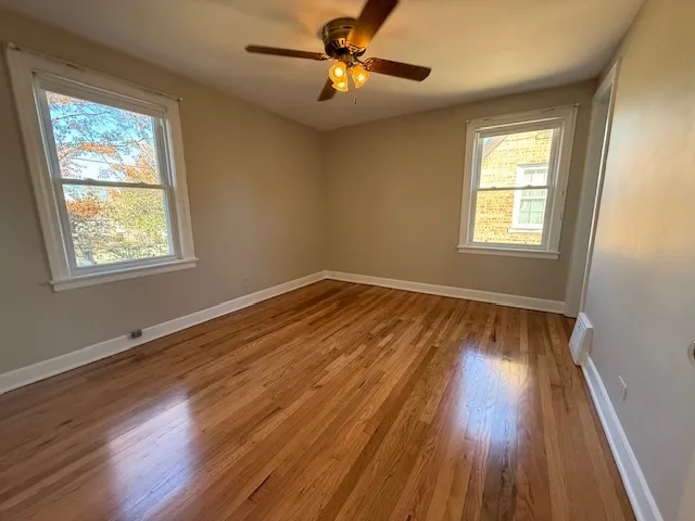 a view of empty room with wooden floor and fan