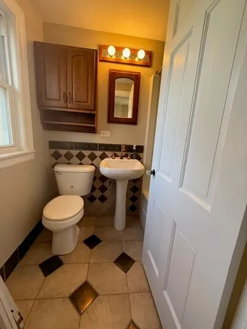 a bathroom with a toilet a sink and a mirror