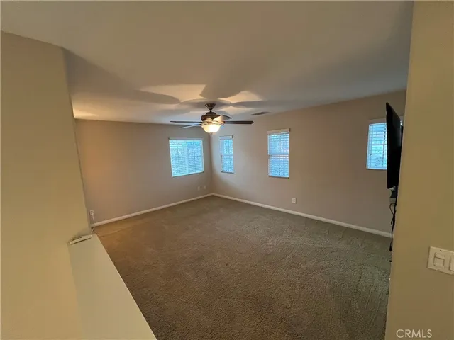 an empty room with windows and chandelier fan