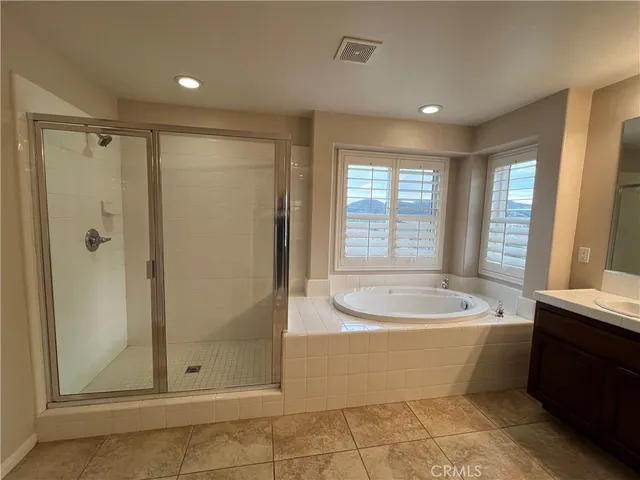 a bathroom with a double vanity sink a large mirror and a bathtub