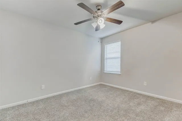 an empty room with a chandelier fan and windows