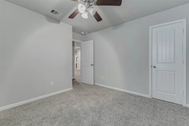 a view of an empty room and a chandelier fan