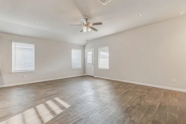 a view of an empty room with a window and wooden floor