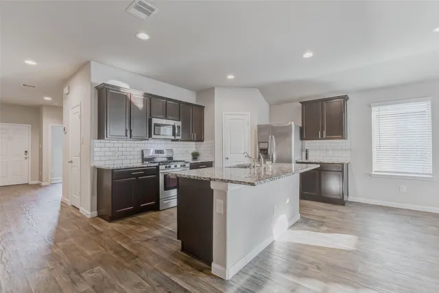 a large kitchen with stainless steel appliances granite countertop a stove refrigerator and a sink