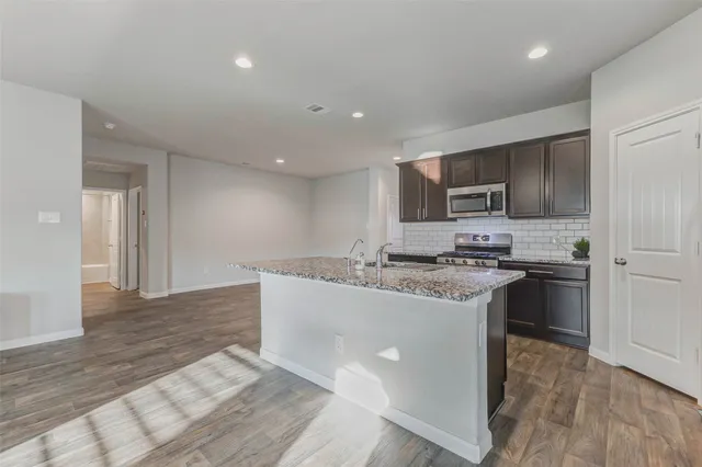 a kitchen with stainless steel appliances granite countertop a sink stove and refrigerator