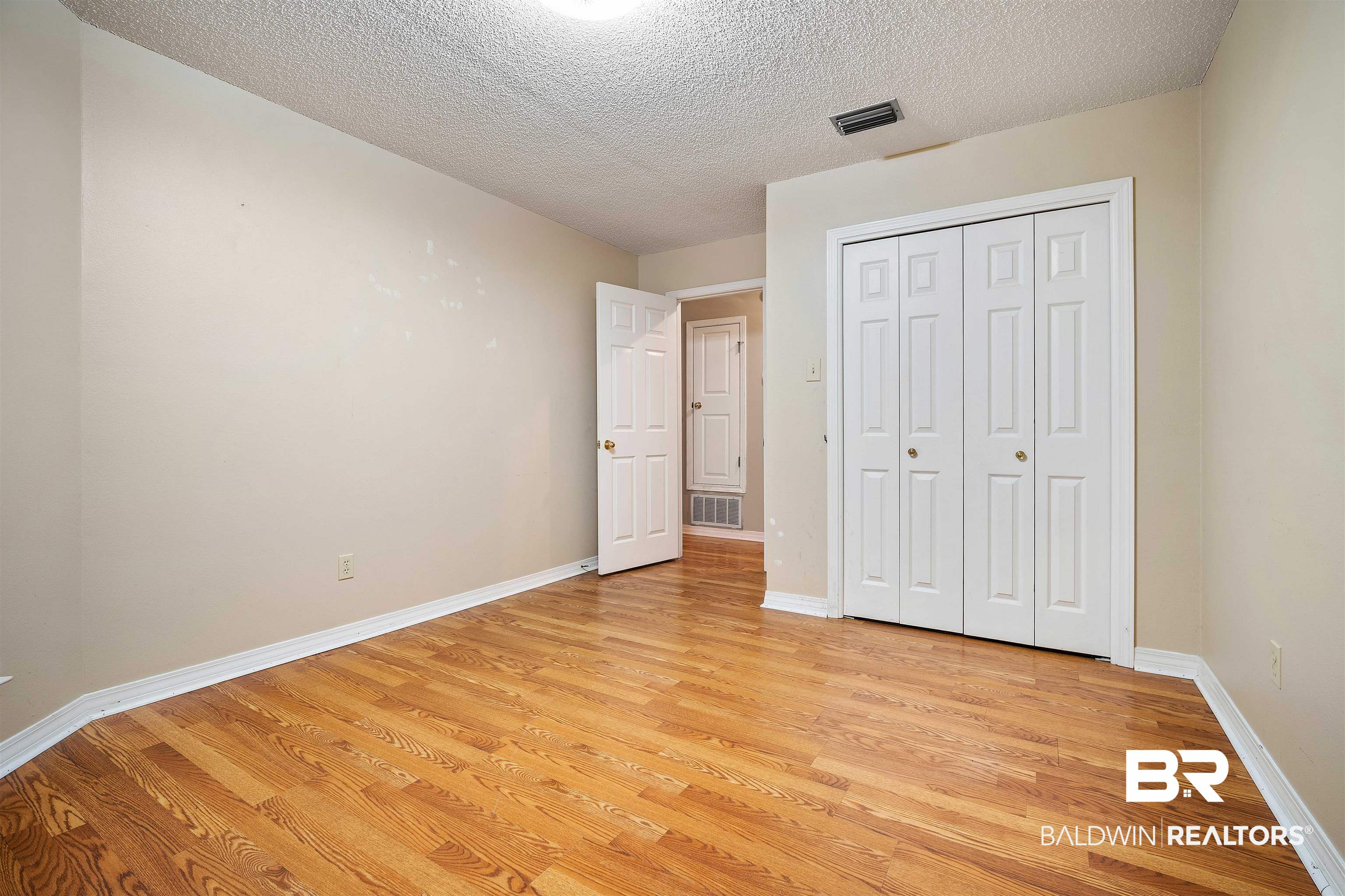 7100 Huntington Court South Mobile, AL 36619 - Photo 24 of 30 Unfurnished bedroom with light hardwood / wood-style floors, a textured ceiling, and a closet