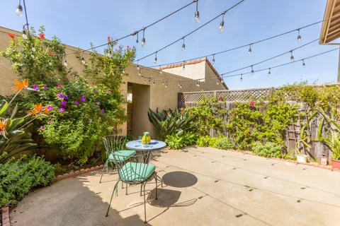 a patio with table and chairs and potted plants