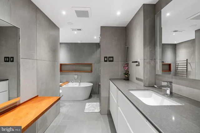 a bathroom with a granite countertop sink a toilet a mirror and bathtub